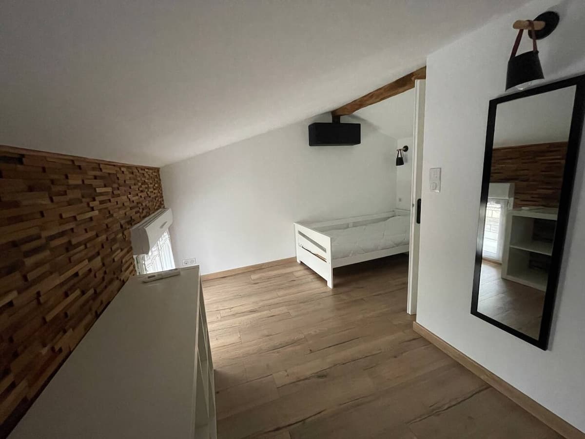 Chambre en mezzanine, mur en lames de bois et grand miroir