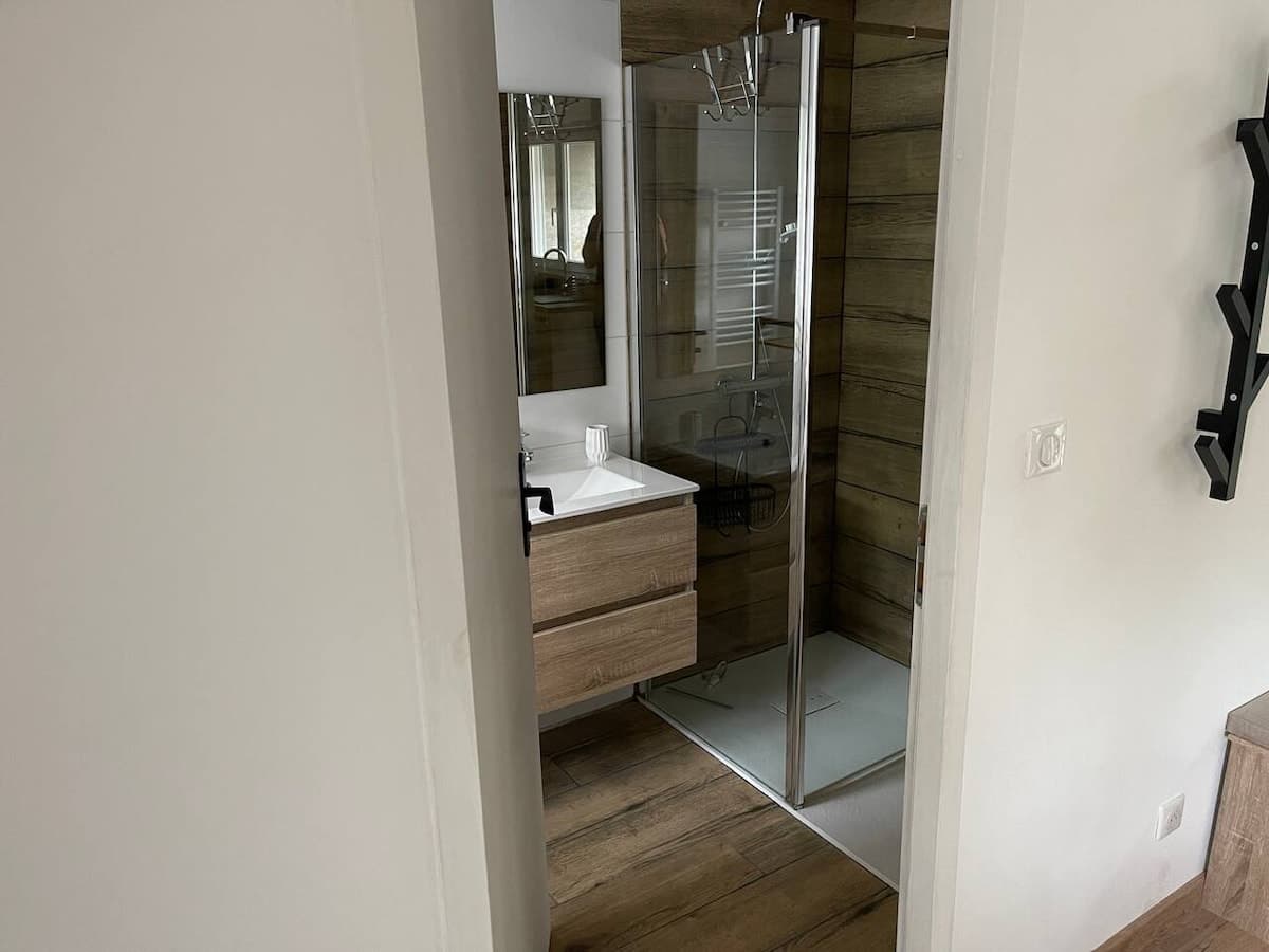 Salle d'eau vue depuis la cuisine : douche vitrée et meuble vasque