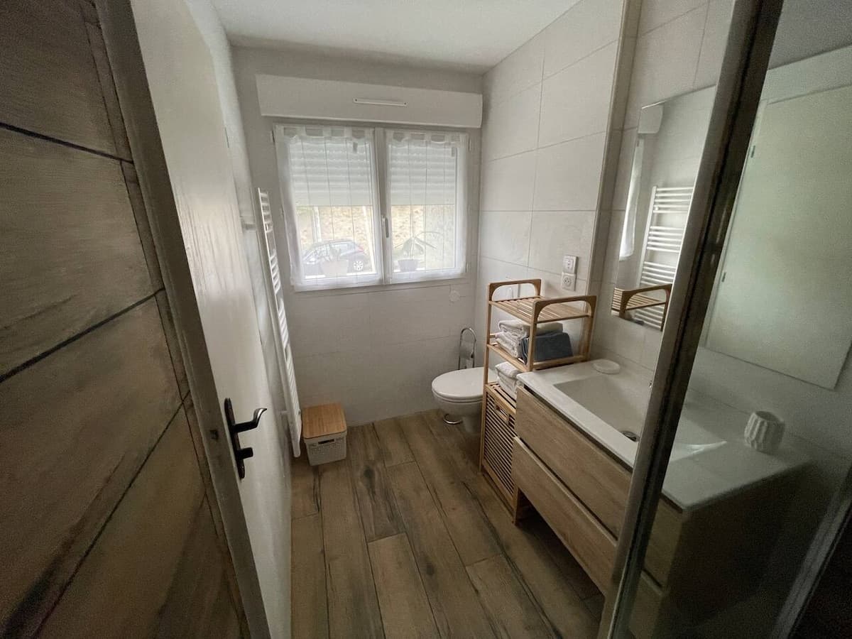 Salle d'eau avec vasque, toilettes et fenêtre